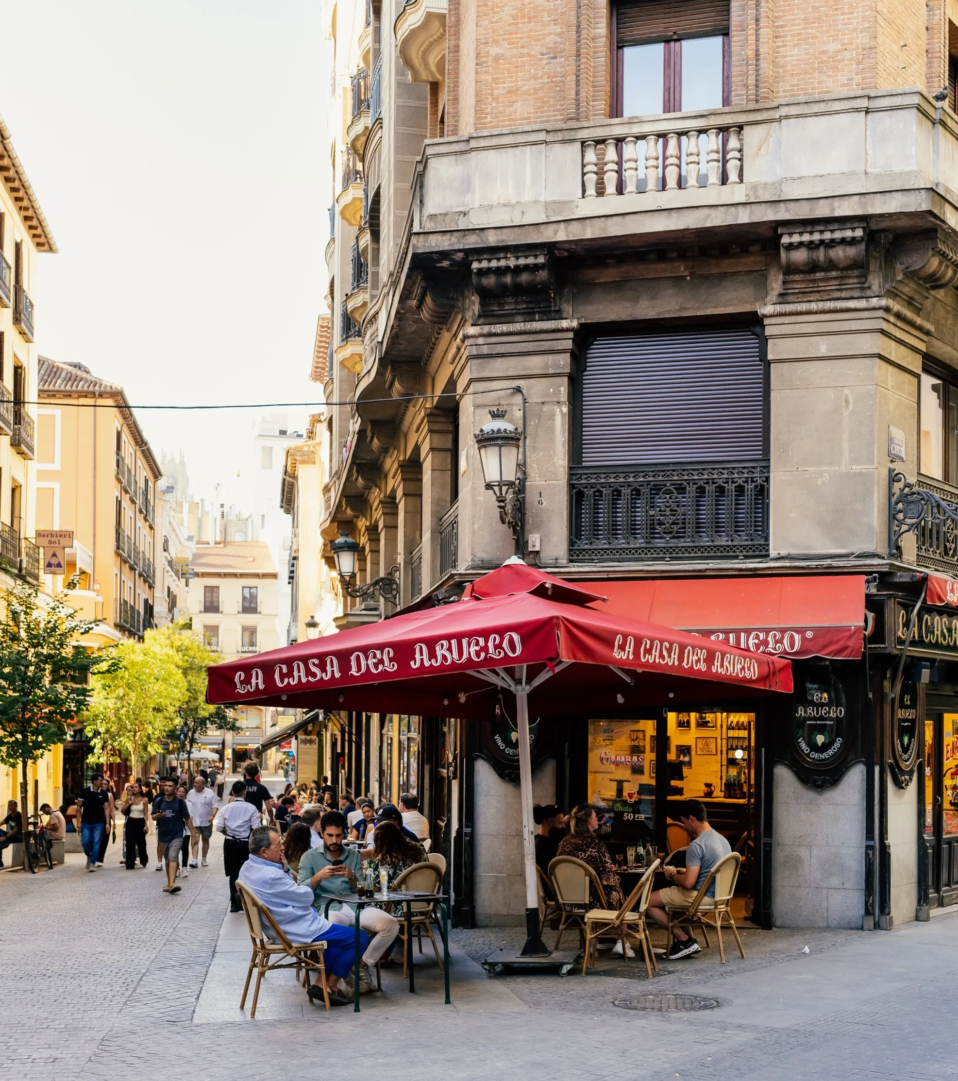 A sunlit pedestrian street in Centro lined with café terraces and balconies